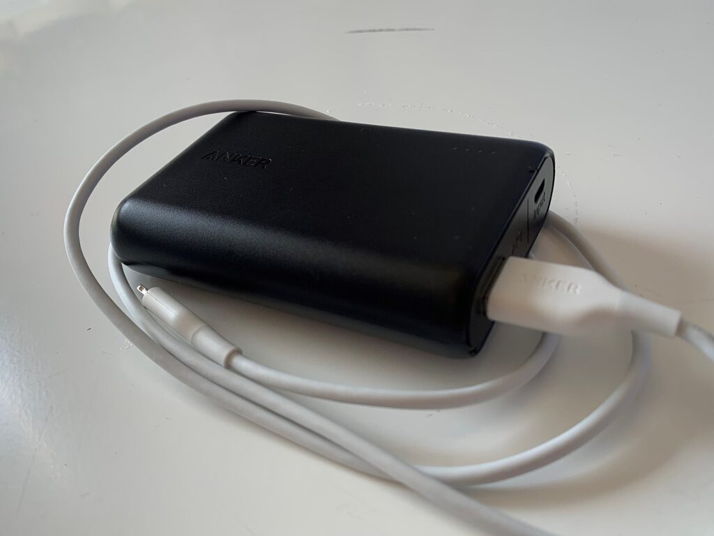 Batería externa conectada por cable a un teléfono encima de una mesa de madera