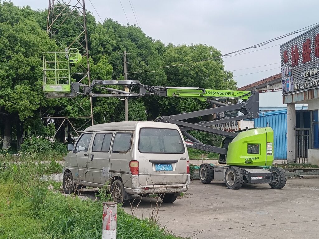 Plataforma elevadora articulada aparcada junto a una fachada durante los trabajos de pintura