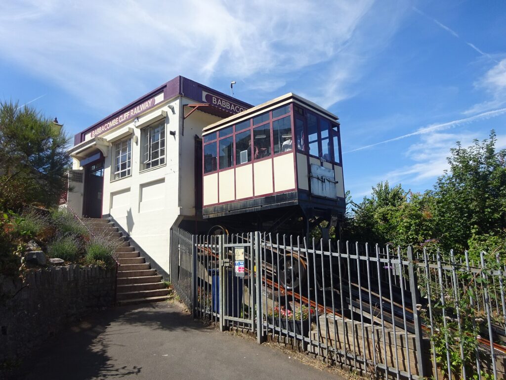 Cabina de funicular subiendo por una pendiente pronunciada junto a una muralla de piedra