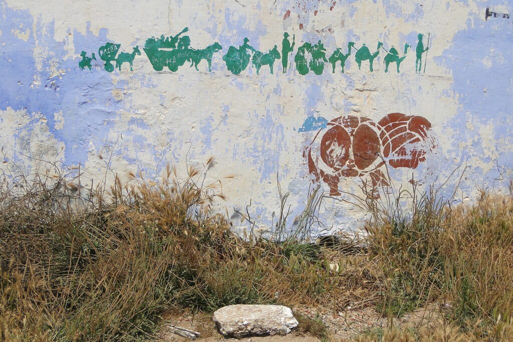 Plantilla de cartón apoyada en un muro junto a rodillos, cinta y botes de pintura