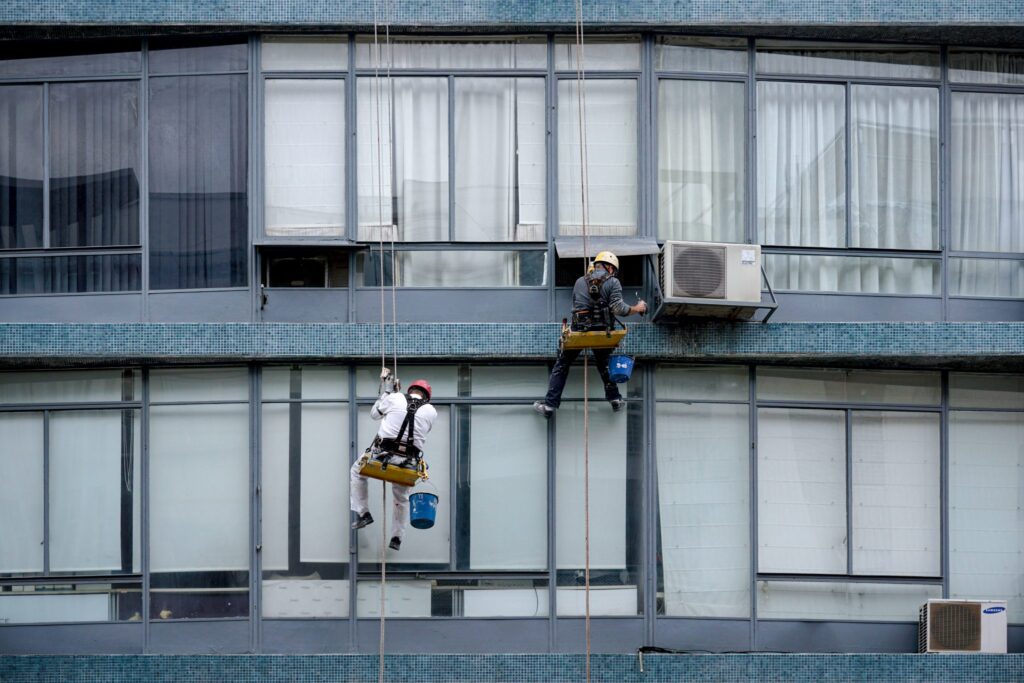 Operario con arnés y casco trabajando sobre una cesta elevadora a varios metros del suelo