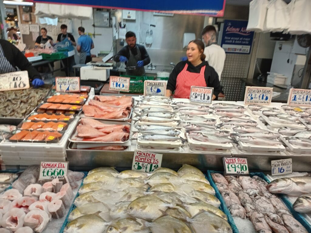 Vendedor colocando hielo y pescado sobre un mostrador en un mercado callejero