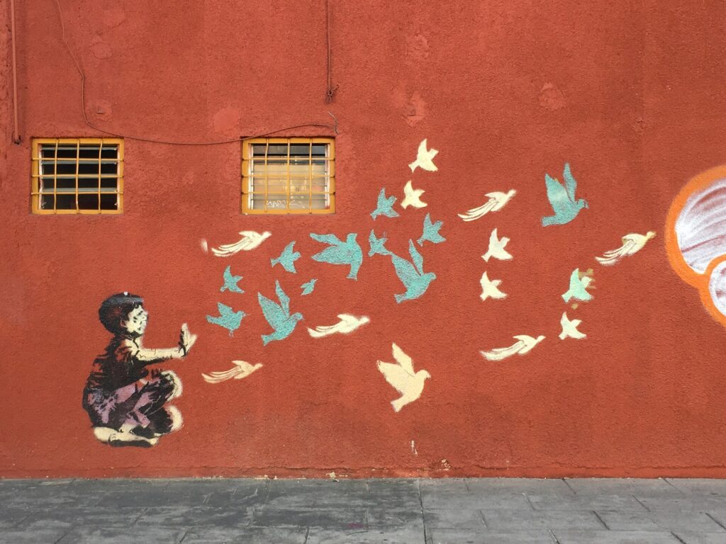 Plantilla pequeña pintada sobre una puerta metálica junto al zócalo de una calle comercial