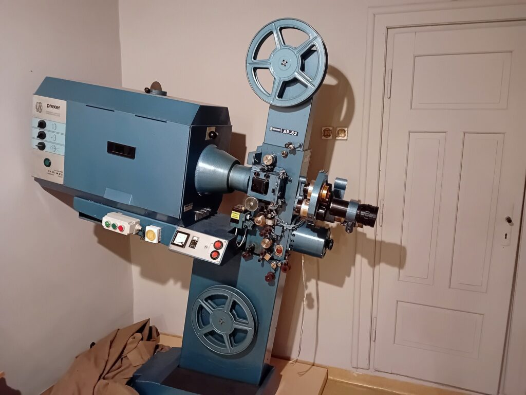 Proyector de cine antiguo con la bobina montada en una sala en penumbra