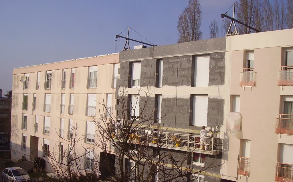 Operarios colocando paneles de aislamiento sobre la fachada de un edificio alto