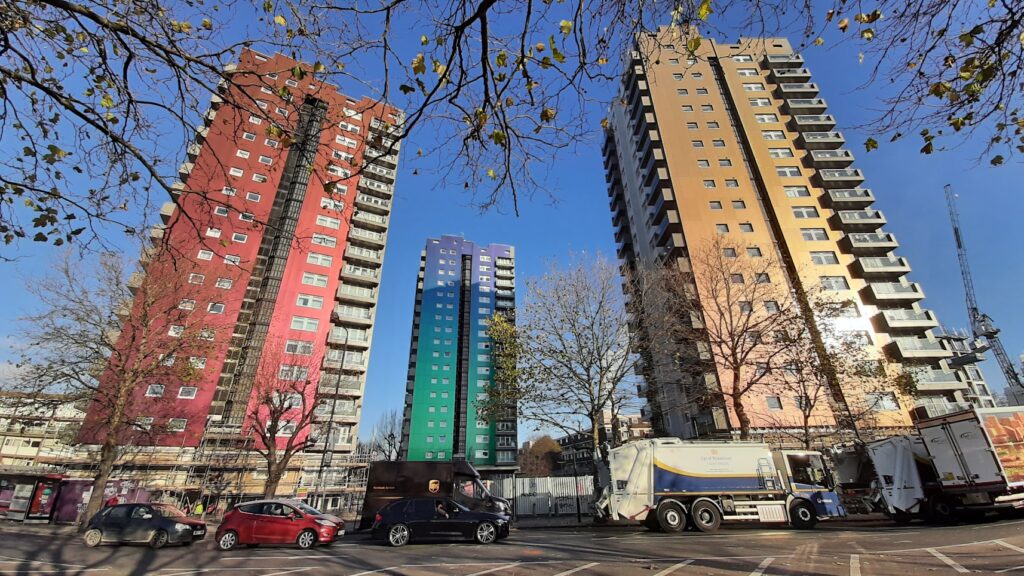 Testero de un bloque alto de viviendas cubierto por un mural comunitario de colores planos